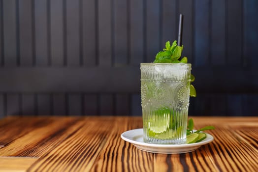 Alcohol cocktail Mojito on wooden table against dark wall with copy space