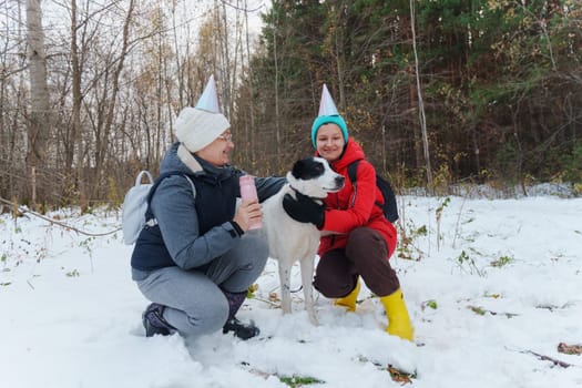 Celebrating in the snowy woods with friends and a loyal dog while wearing festive hats and enjoying a joyful winter day