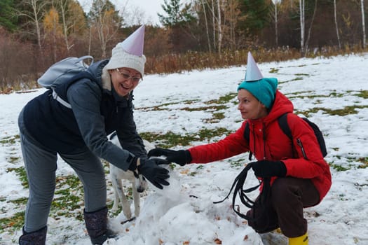 Joyful moments creating a snowman with friends in a snowy park during winter celebrations