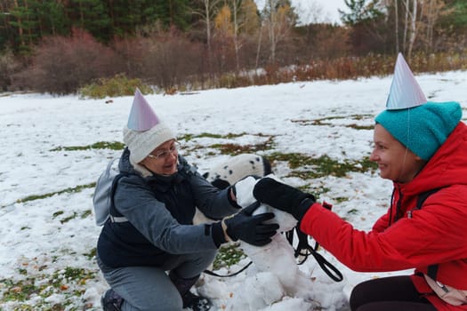 Joyful moments creating a snowman with friends in a snowy park during winter celebrations