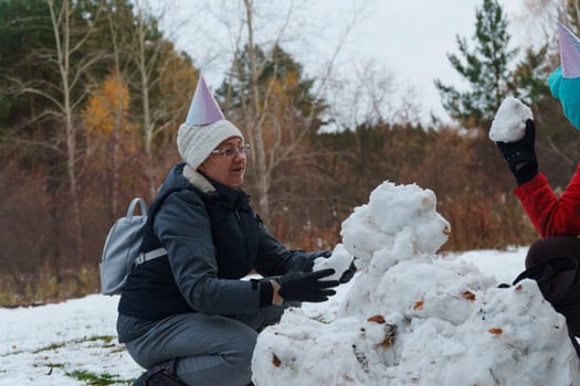 Laughter fills the air as cheerful friends create snowballs, donning festive hats in a snowy landscape.