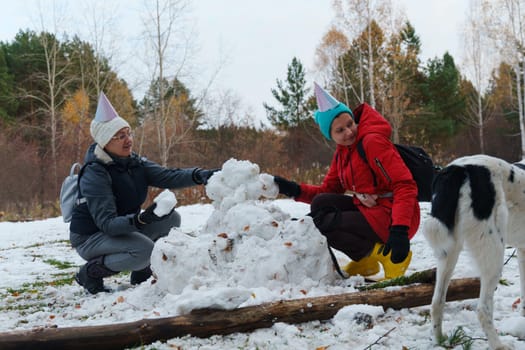 Laughter fills the air as cheerful friends create snowballs, donning festive hats in a snowy landscape.