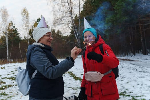 Celebrating joyfully in a snowy forest with sparklers and festive hats during a chilly winter gathering
