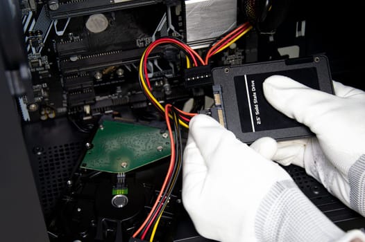 The mechanic is connecting the wires to the 2.5 inch SSD hard drive.