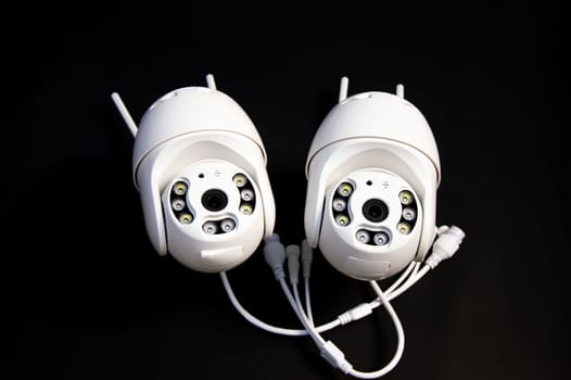 Two white IP cameras placed on a black background