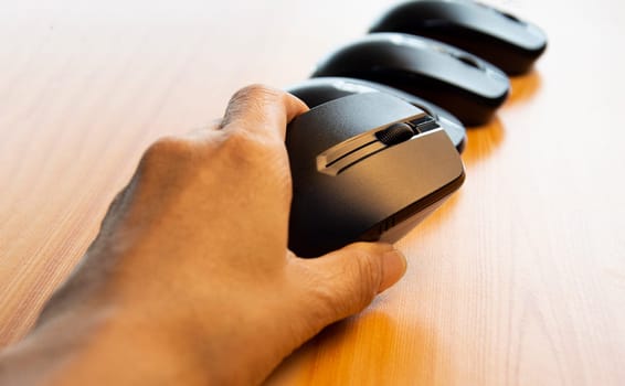 Black wireless mouse in hand on wooden background