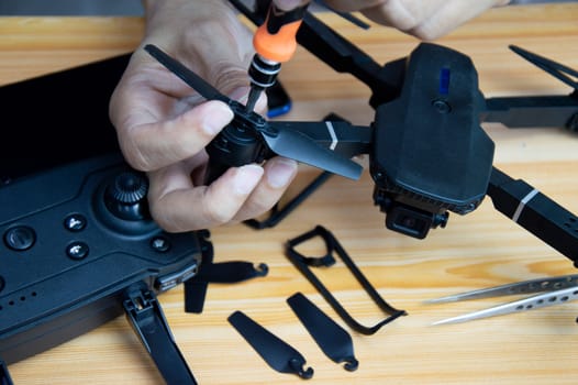 Professional mechanic repairing a drone with a small screwdriver on the table with various tools in modern workshop