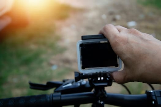 Male hand adjusting action camera on bicycle