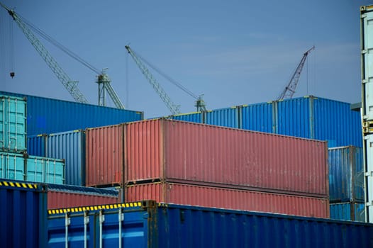 containers awaiting transport and at the back there is a crane to lift the cargo container