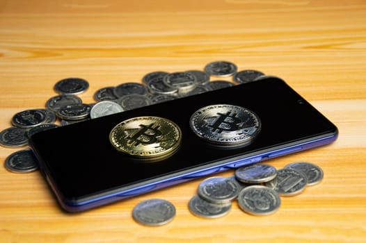 Gold coins and Bitcoin placed on smartphone. Concept of virtual currency, digital wallet, financial application.