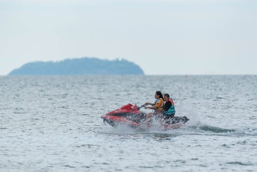 Rayong, Thailand - December 28, 2024 : Unidentified asian people travel and ride playing scooter or jetski with happy fun at sea LaemMaePhim beach.