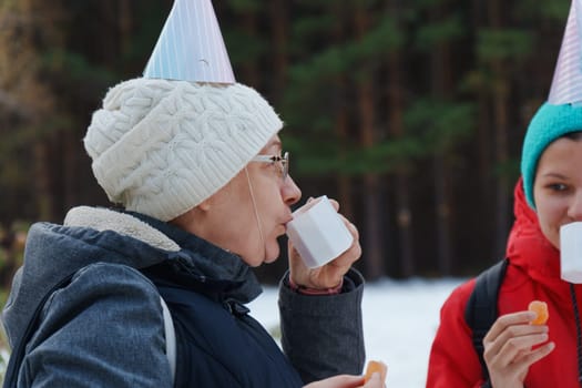 Joyful gathering in the woods with festive hats and warm drinks during a winter celebration