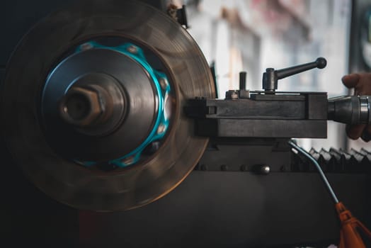 Car mechanic or serviceman disassembly and checking a disc brake and asbestos brake pads for fix and repair problem at car garage or repair shop