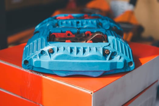 Car mechanic or serviceman disassembly and checking a disc brake and asbestos brake pads for fix and repair problem at car garage or repair shop