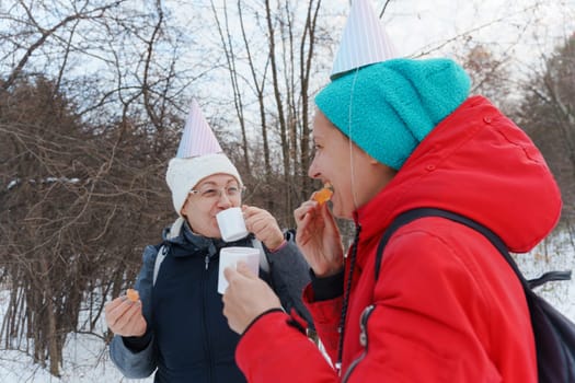 Joyful gathering in the woods with festive hats and warm drinks during a winter celebration