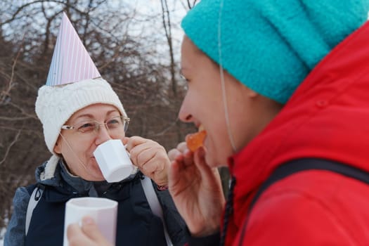 Celebrating friendship in a snowy forest with warm drinks and playful hats during a winter gathering