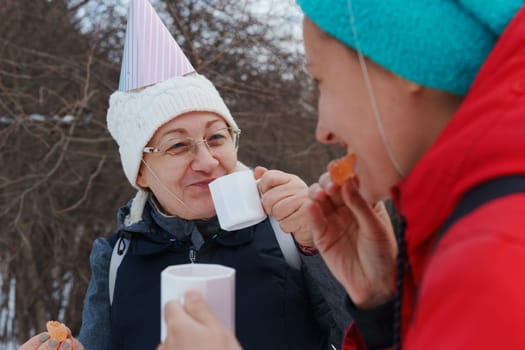 Celebrating friendship in a snowy forest with warm drinks and playful hats during a winter gathering