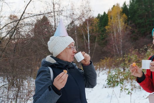 Celebrating friendship in a snowy forest with warm drinks and playful hats during a winter gathering