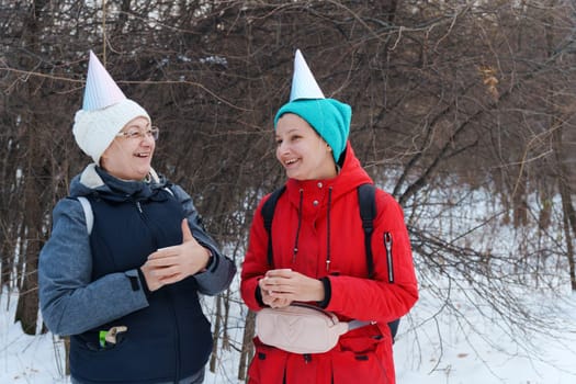 Winter celebration in the forest with friends wearing festive hats and enjoying warm drinks