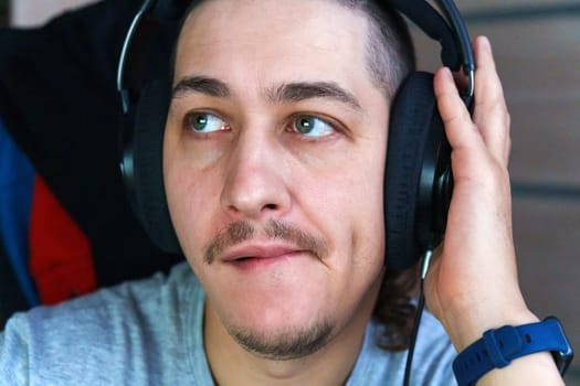 A man listens to music with deep concentration, showcasing a thoughtful expression. He wears headphones