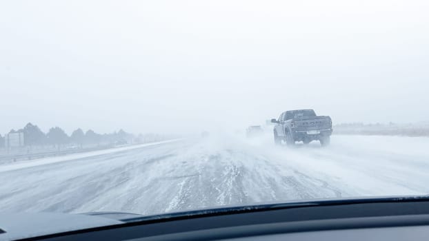 Denver, Colorado, USA-January 15, 2024-Several vehicles face blinding snowfall and slippery conditions while traveling on an interstate, with the storm reducing visibility and the road boundaries barely discernible.