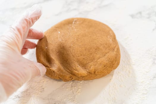 Straight-on view of amber gingerbread cookie dough resting on a floured marble countertop, prepared for the next baking step.