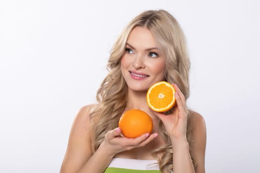 A vibrant woman joyfully shows a bright orange fruit, highlighting the importance of health and freshness