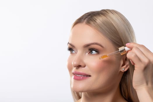 A woman skillfully uses a dropper to apply her favorite serum, ensuring her skin glows before heading out