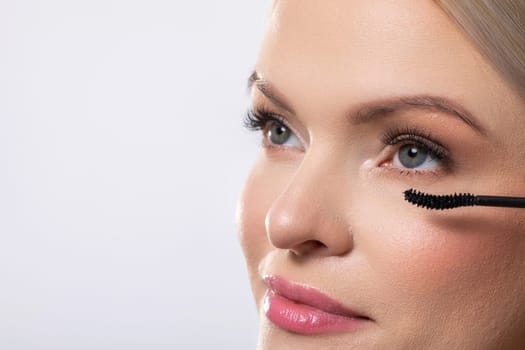 Closeup of a woman meticulously applying her mascara, showcasing her beauty, makeup skills, and elegant appearance