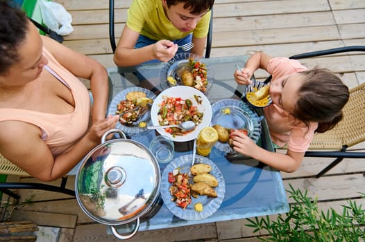 Family sitting around a table outdoors enjoying a meal of vibrant homemade food together.