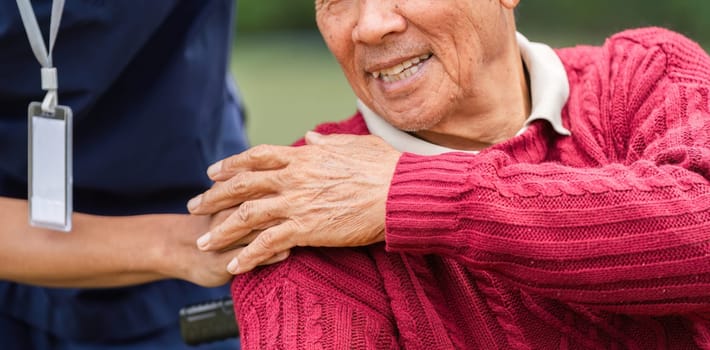 A heartwarming close-up of an elderly man's smiling face while a caregiver's hand rests on his shoulder, showcasing compassion in a beautiful garden setting.