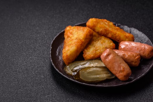 Hash browns with potatoes and onions, salt and spices on a dark concrete background