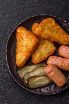 Hash browns with potatoes and onions, salt and spices on a dark concrete background