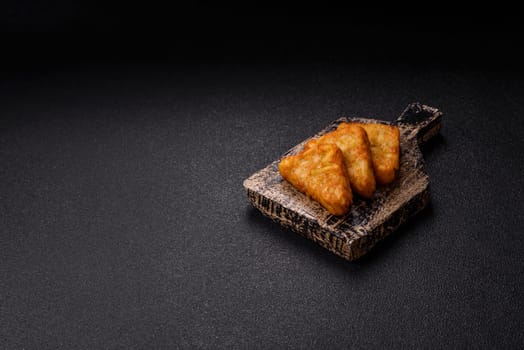 Hash browns with potatoes and onions, salt and spices on a dark concrete background