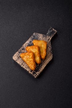 Hash browns with potatoes and onions, salt and spices on a dark concrete background
