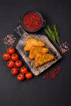 Hash browns with potatoes and onions, salt and spices on a dark concrete background