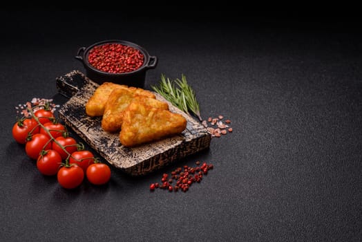 Hash browns with potatoes and onions, salt and spices on a dark concrete background