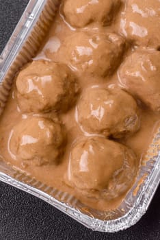 Meatballs with salt and spices in creamy caramel sauce on a dark concrete background