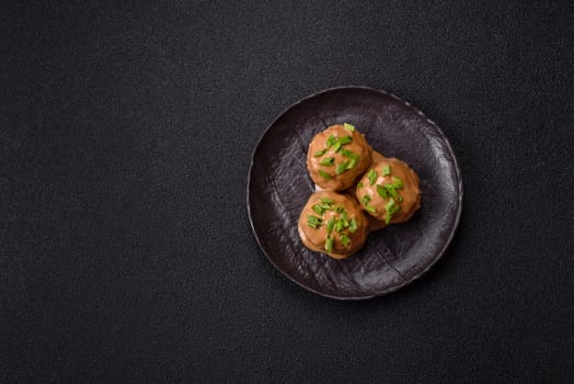Meatballs with salt and spices in creamy caramel sauce on a dark concrete background