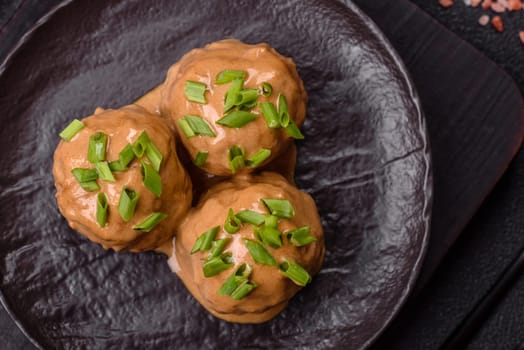 Meatballs with salt and spices in creamy caramel sauce on a dark concrete background