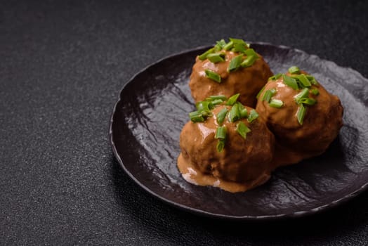 Meatballs with salt and spices in creamy caramel sauce on a dark concrete background