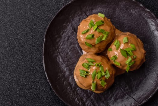 Meatballs with salt and spices in creamy caramel sauce on a dark concrete background