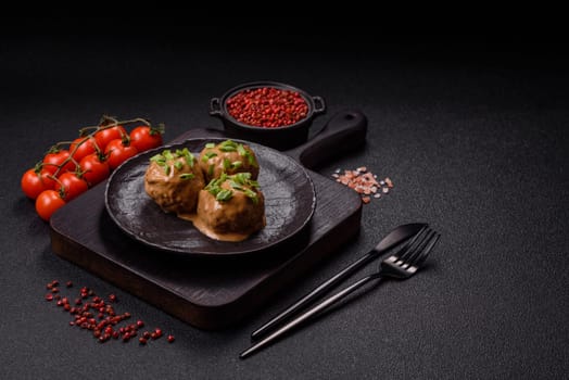 Meatballs with salt and spices in creamy caramel sauce on a dark concrete background