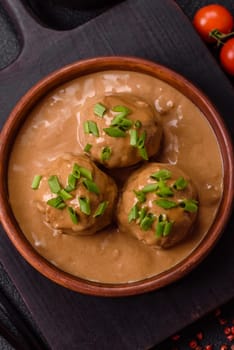 Meatballs with salt and spices in creamy caramel sauce on a dark concrete background