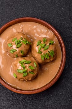 Meatballs with salt and spices in creamy caramel sauce on a dark concrete background