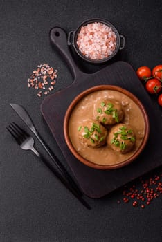 Meatballs with salt and spices in creamy caramel sauce on a dark concrete background