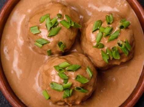 Meatballs with salt and spices in creamy caramel sauce on a dark concrete background