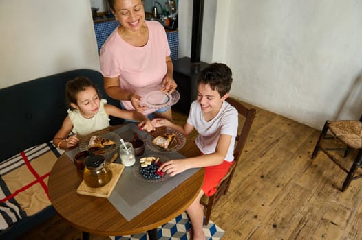 A cheerful family spends quality time together during breakfast, sharing food and smiles in a cozy home environment.