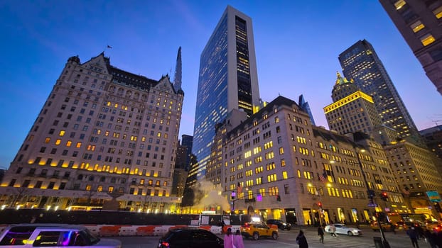 Modern look of a big metropolitan city with illuminated skyscrapers and classic architecture under a clear blue sky. Urban hustle and warm lighting create a vibrant and captivating cityscape. good for multimedia background