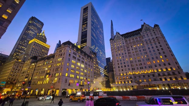 Modern look of a big metropolitan city with illuminated skyscrapers and classic architecture under a clear blue sky. Urban hustle and warm lighting create a vibrant and captivating cityscape. good for multimedia background